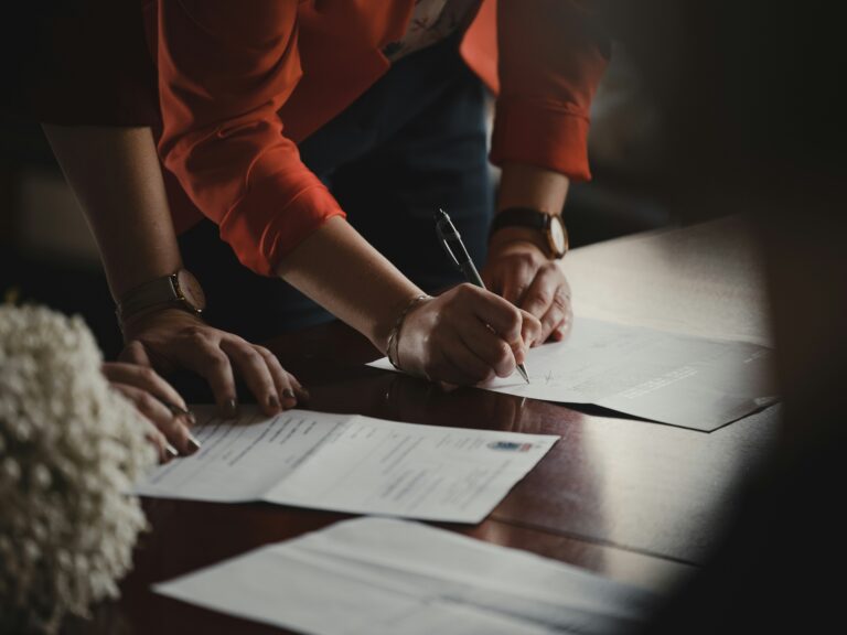 two people signing a contract